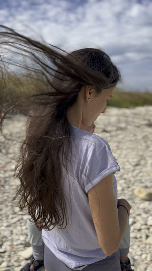 T-Shirt Lasse in Lavender von hinten, Laura mit wehenden Haaren am Strand