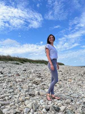 Laura trägt das Unisex T-Shirt Lasse in Lavender an einem Kiesstrand