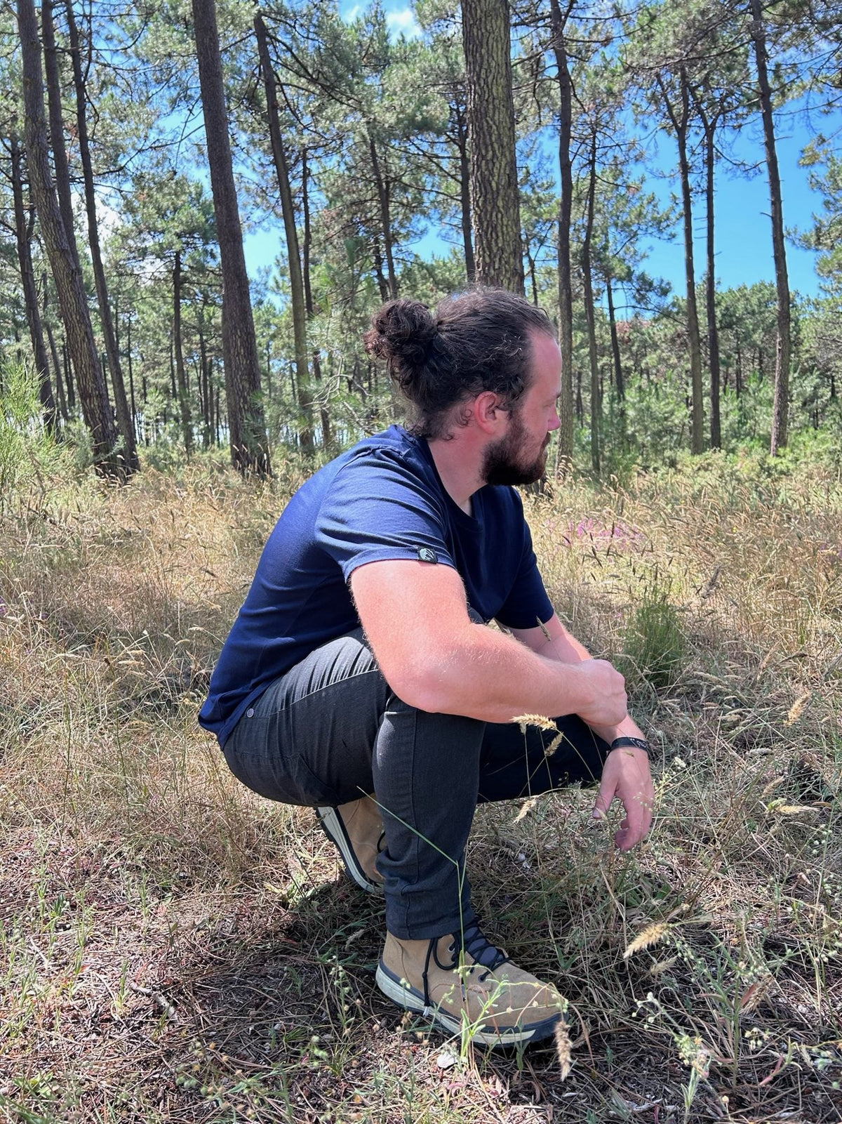 Philipp trägt das Unisex T-Shirt Lasse in Worker Blue im Kiefernwald